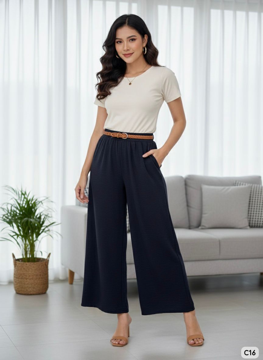Woman wearing a white top and navy wide-leg pants in a living room setting.